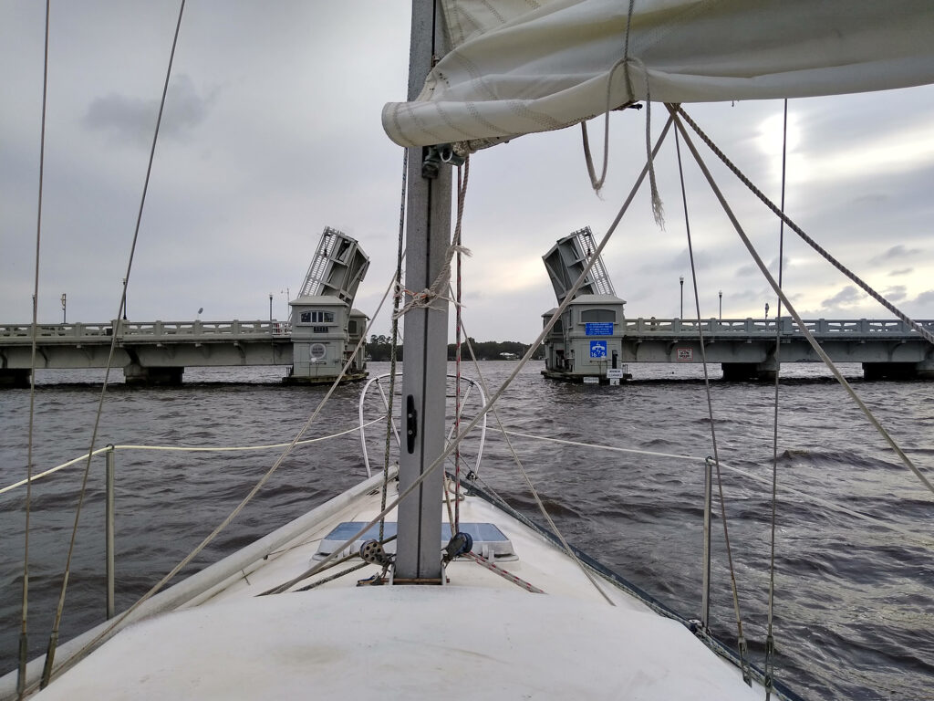 Sailboat approaching a bridge.