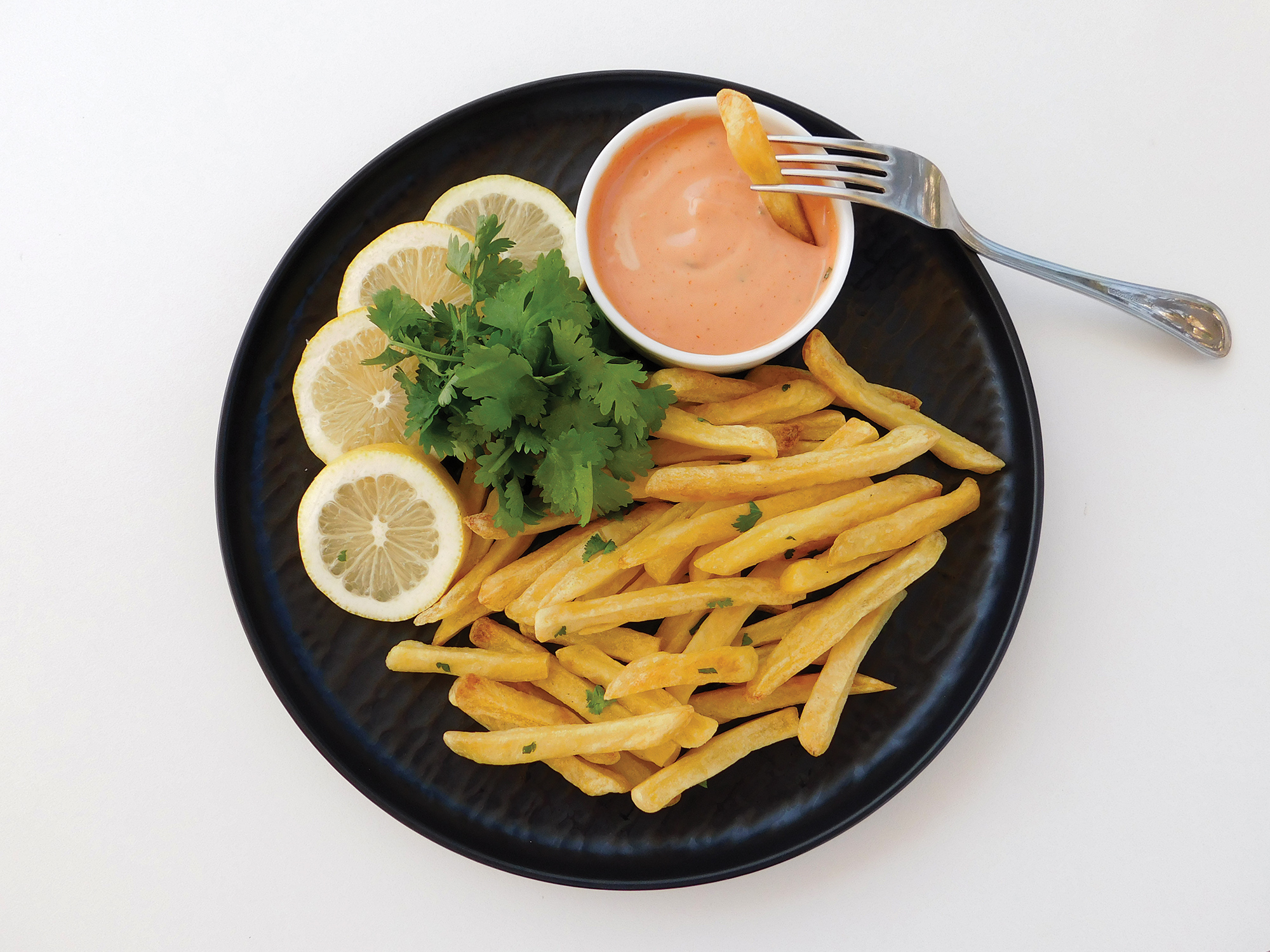 French fries with dipping sauce and lemon wedges