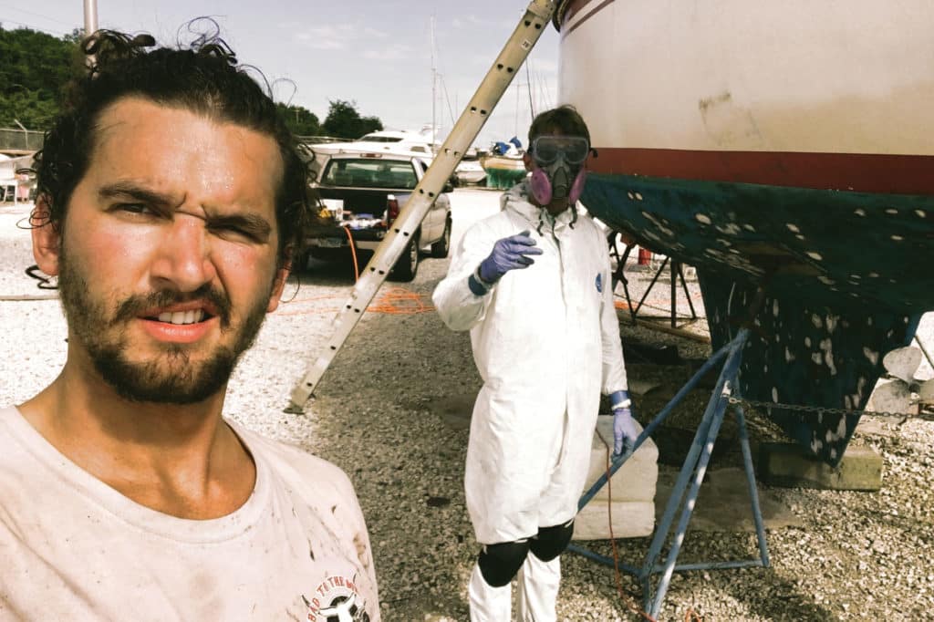 Two guys standing next to a project sailboat.