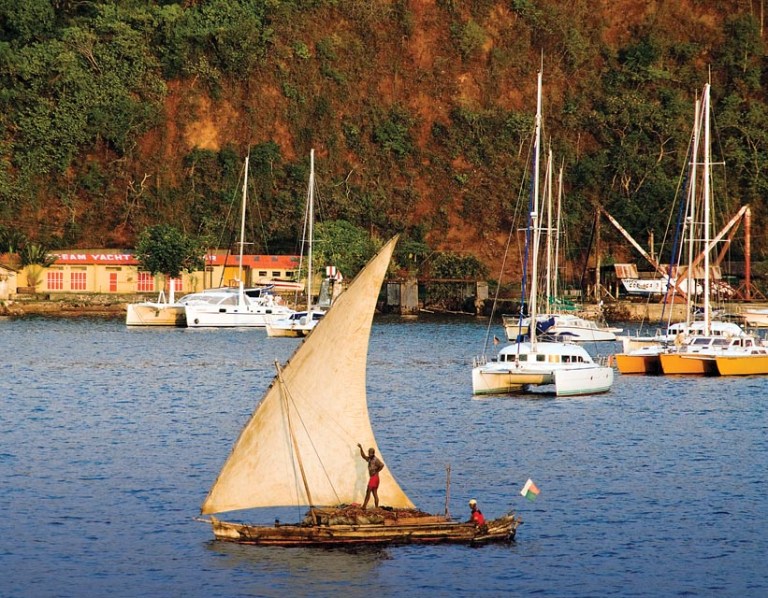 Loaded with reeds for building huts, a laka outrigger slips by the Dream Yacht Charter base in Crater Bay, Nosy Be.