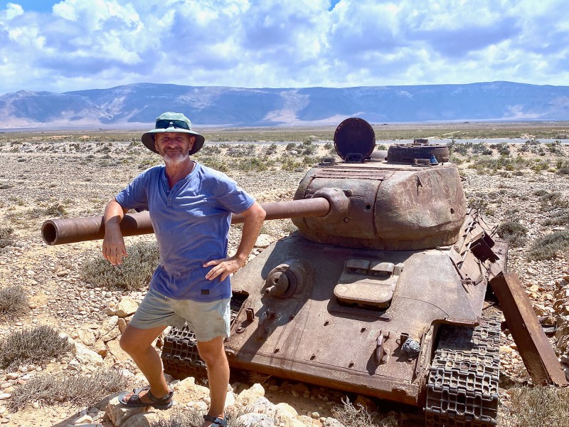 Man posing next to Soviet era tank